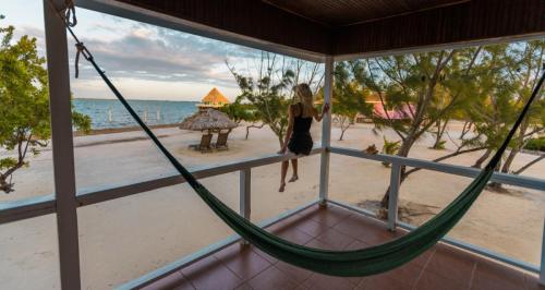 Woman sitting on the railing of a beachfront cabana at sunset.
