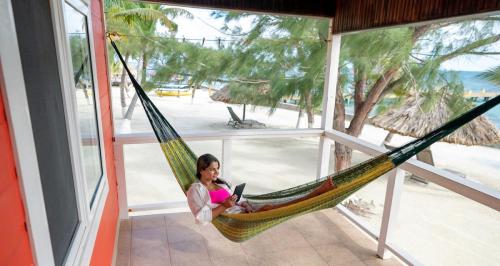 Woman relaxing in a hammock on a beachfront cabana porch, reading with an Caribbean Sea view.